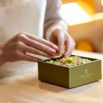 업사이클링 제품 패키징의 중요성 - **Prompt 1: Artisan's Delicate Touch with Petal-Infused Upcycled Packaging**
    A close-up, eye-lev...